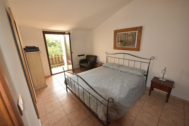 Camera da letto con letto matrimoniale, balcone e vista sul bosco